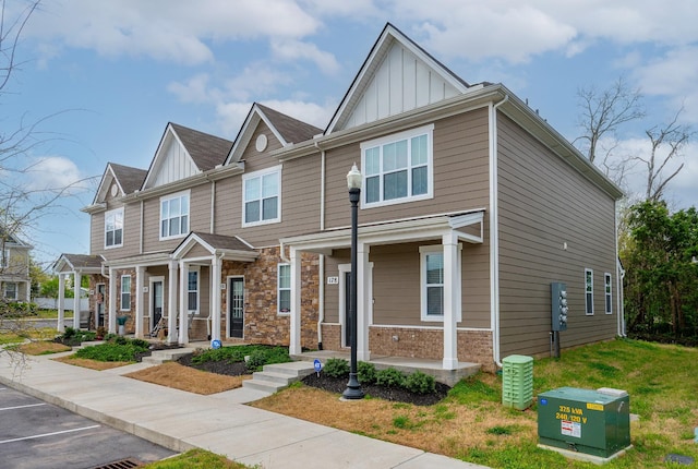 townhome / multi-family property featuring board and batten siding, stone siding, covered porch, and uncovered parking