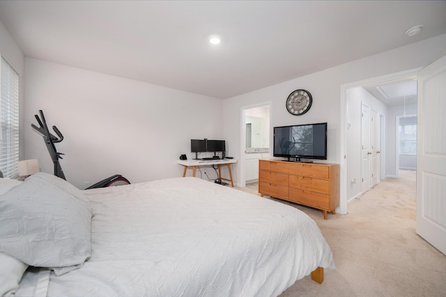 bedroom with ensuite bathroom, baseboards, attic access, and light colored carpet