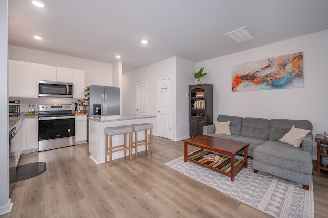 living area featuring baseboards, light wood-type flooring, and recessed lighting