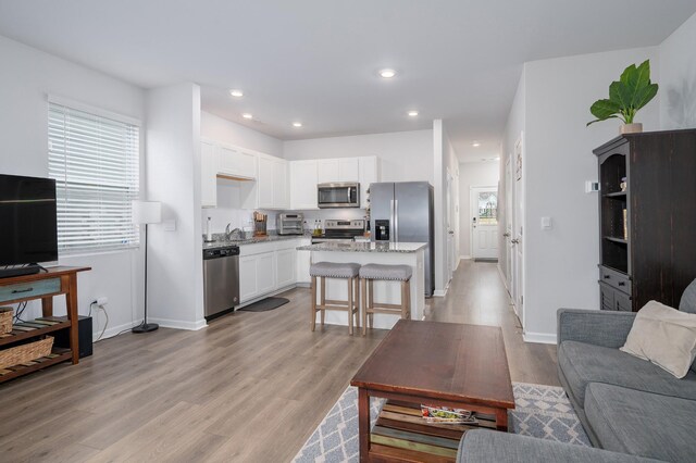 living area featuring baseboards, recessed lighting, a toaster, and light wood-style floors