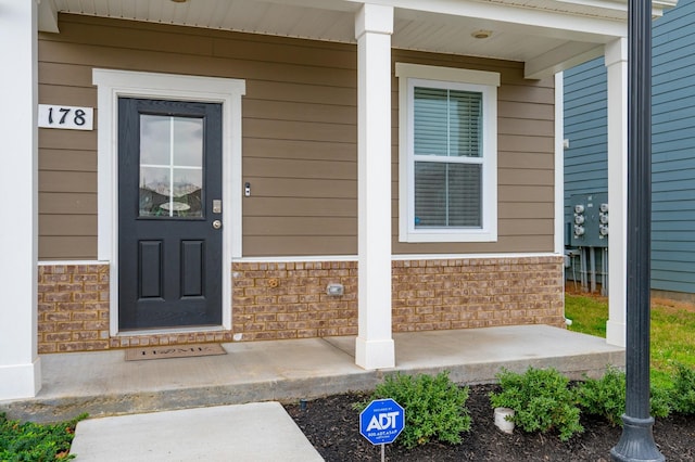 doorway to property featuring brick siding and a porch