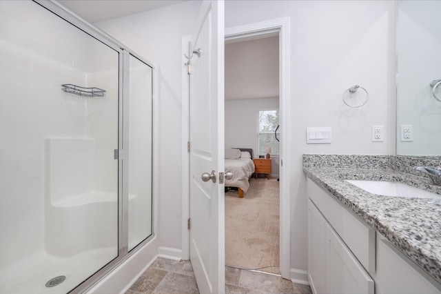 bathroom featuring stone finish flooring, baseboards, a stall shower, and vanity