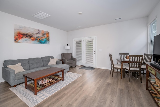 living room featuring wood finished floors, baseboards, and visible vents