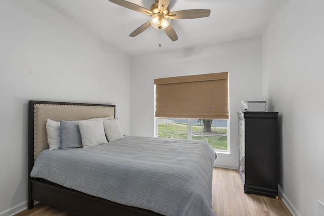 bedroom with light wood-style floors, ceiling fan, and baseboards