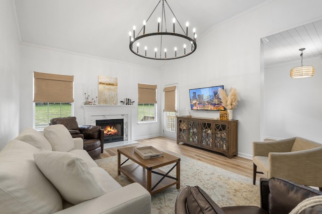 living area with plenty of natural light, a premium fireplace, an inviting chandelier, and wood finished floors