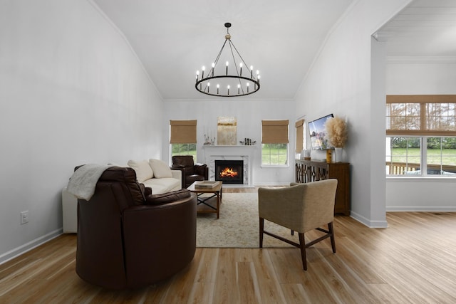 living room with a chandelier, light wood-style floors, baseboards, and crown molding