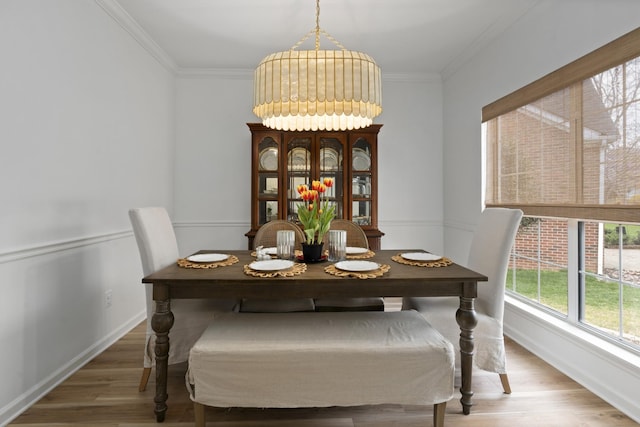 dining area with ornamental molding, baseboards, and light wood finished floors