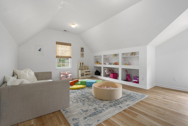 game room with vaulted ceiling, visible vents, wood finished floors, baseboards, and built in shelves