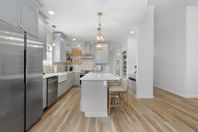 kitchen with open shelves, wall chimney exhaust hood, a sink, light countertops, and appliances with stainless steel finishes