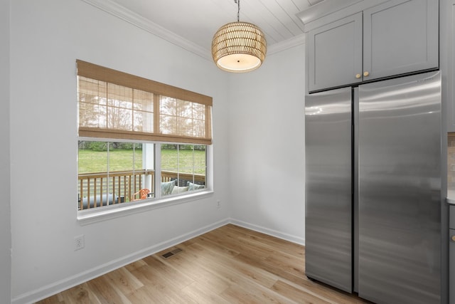kitchen with visible vents, baseboards, freestanding refrigerator, crown molding, and light wood-style flooring
