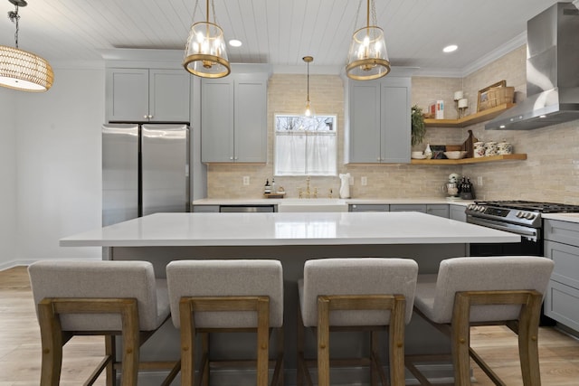 kitchen with wall chimney range hood, recessed lighting, stainless steel appliances, light wood finished floors, and a sink