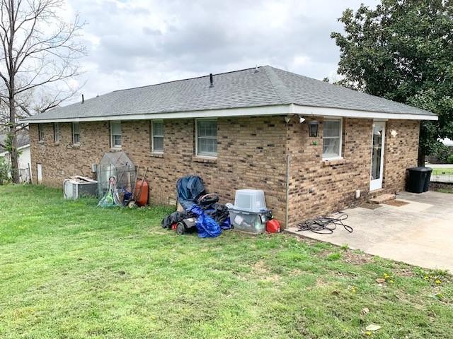 1844 Holloway Cir, Lebanon, TN 37090 - back of property featuring brick siding, a shingled roof, a patio area, and a lawn