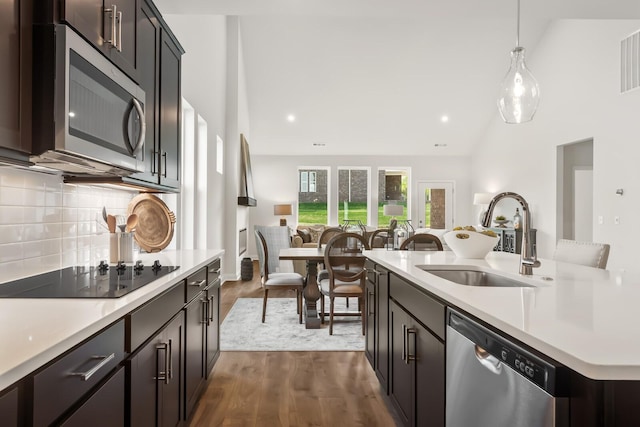 kitchen featuring light countertops, appliances with stainless steel finishes, open floor plan, and a sink
