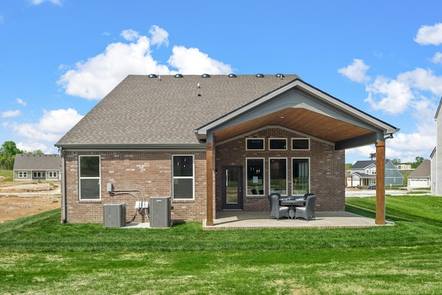 rear view of house featuring brick siding, a yard, a patio area, and central AC