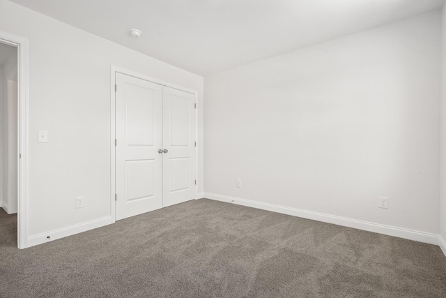 unfurnished bedroom with baseboards, carpet flooring, and a closet