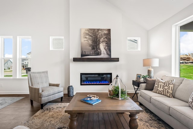 living room with lofted ceiling, a healthy amount of sunlight, wood finished floors, and baseboards