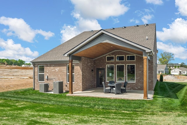 back of house featuring brick siding, a lawn, a patio, and central AC unit