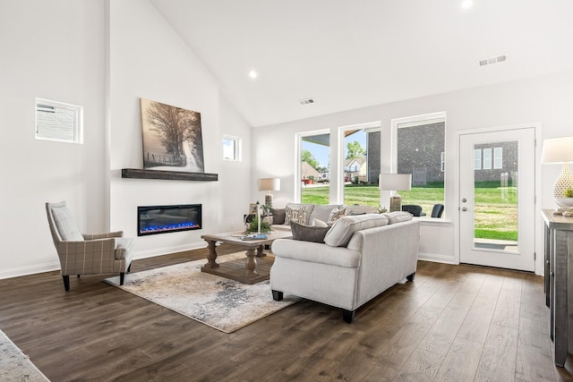 living room with high vaulted ceiling, dark wood-style floors, a glass covered fireplace, baseboards, and visible vents