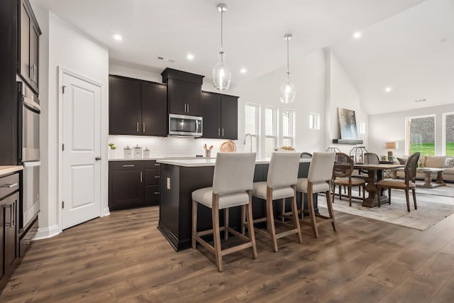 kitchen featuring stainless steel microwave, a kitchen island, light countertops, and a breakfast bar area