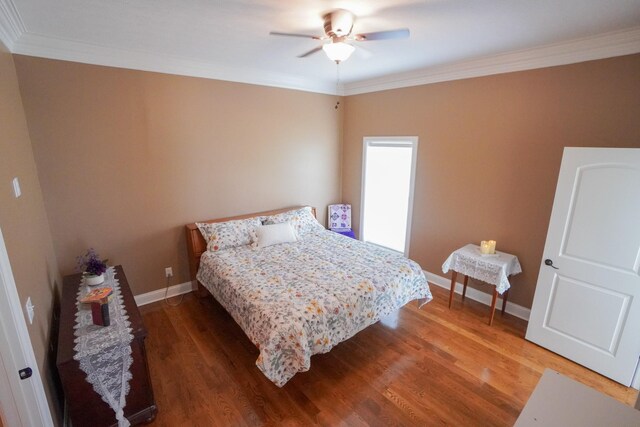 bedroom featuring baseboards, ornamental molding, a ceiling fan, and wood finished floors