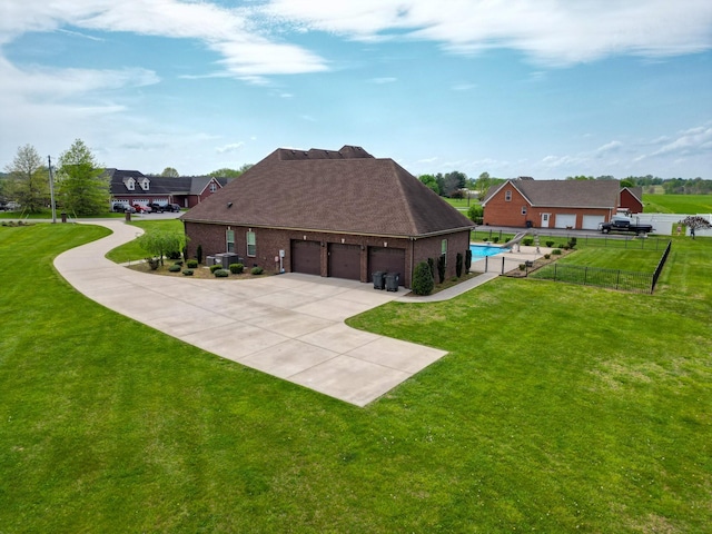 rear view of property featuring a garage, a yard, brick siding, concrete driveway, and fence