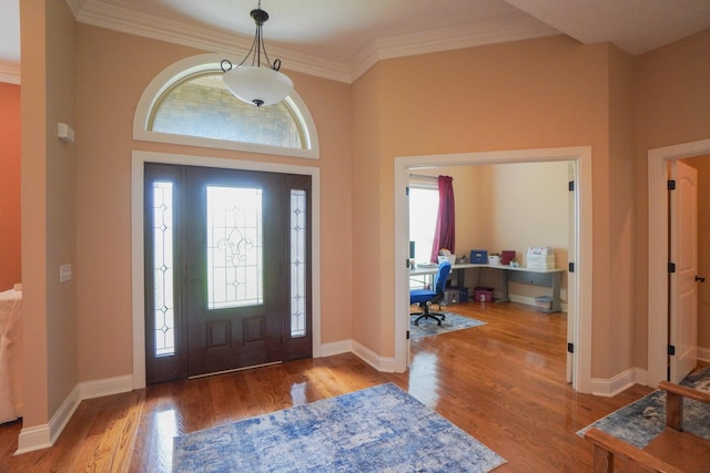 entryway with ornamental molding, wood finished floors, and baseboards
