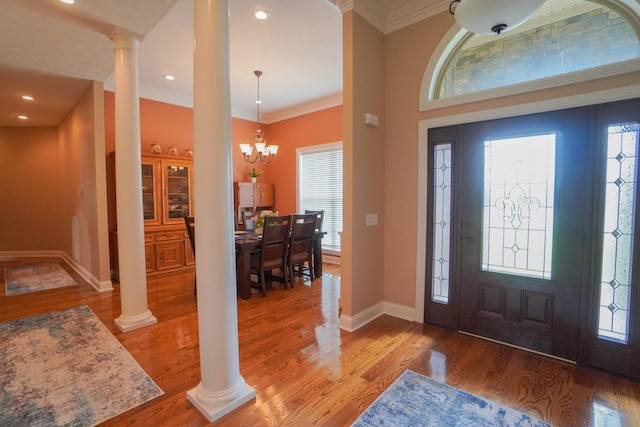 foyer entrance with light wood finished floors, baseboards, a wealth of natural light, and ornate columns