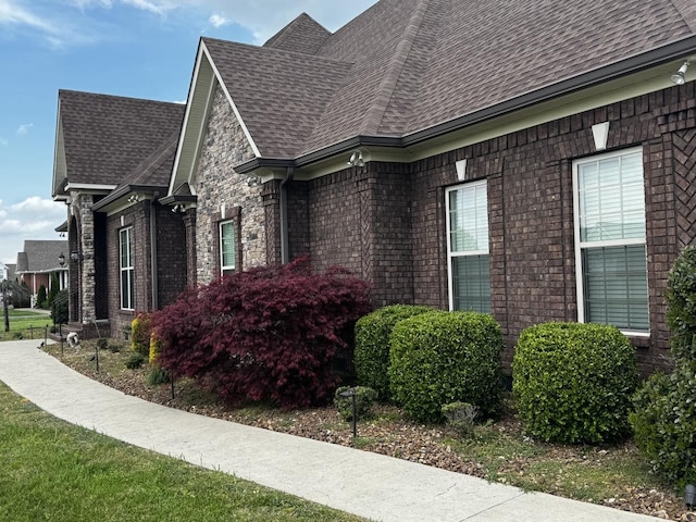 view of property exterior featuring brick siding and roof with shingles