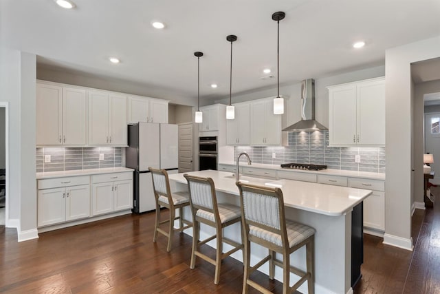 565 Kipton Trl, Lebanon, TN 37087 - kitchen featuring wall chimney range hood, tasteful backsplash, appliances with stainless steel finishes, light countertops, and dark wood-style flooring