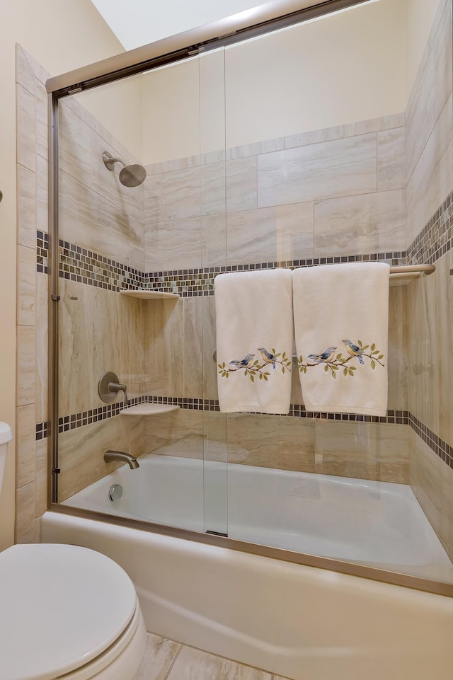 bathroom with toilet and shower / bath combination with glass door