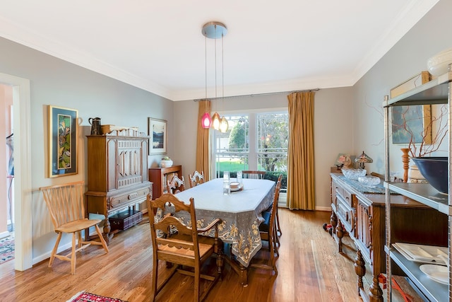 dining room featuring light wood finished floors, baseboards, and ornamental molding