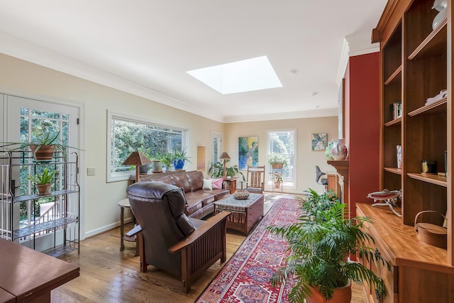 living room with light wood-style floors, baseboards, crown molding, and a skylight