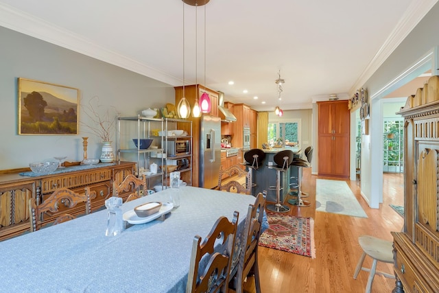 dining room with ornamental molding, light wood-style flooring, and recessed lighting