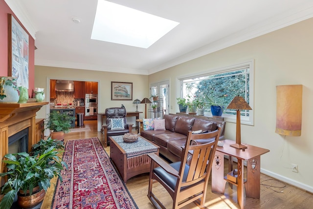 living area featuring light wood-style flooring, baseboards, crown molding, and a skylight