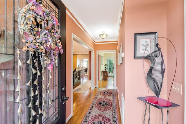 entryway with crown molding and wood finished floors