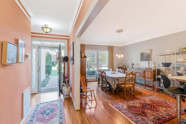 foyer featuring visible vents, ornamental molding, and light wood-style flooring