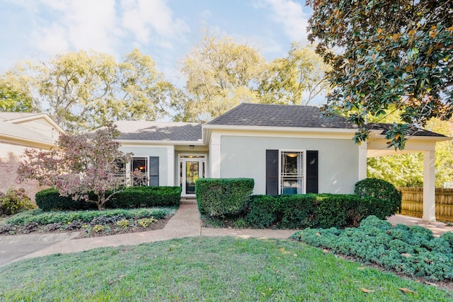 ranch-style house with roof with shingles, a front lawn, fence, and stucco siding