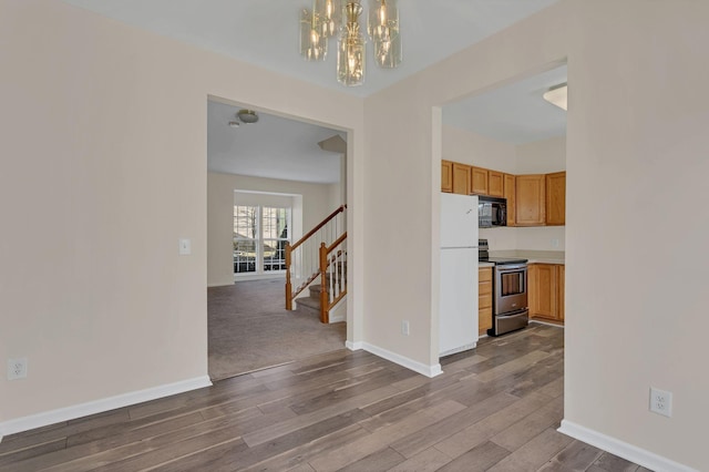 interior space featuring baseboards, an inviting chandelier, wood finished floors, and stairs