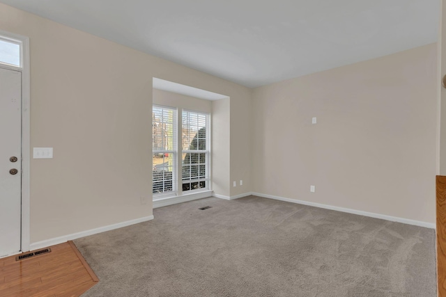 carpeted spare room with baseboards and visible vents