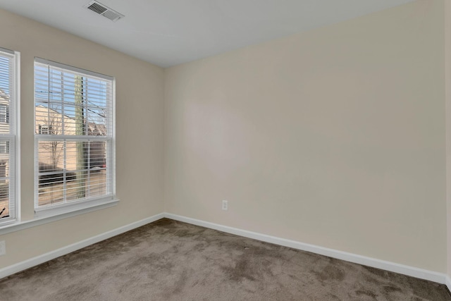 carpeted spare room featuring visible vents and baseboards