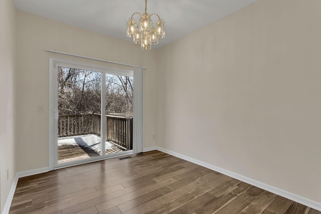 interior space featuring a chandelier, wood finished floors, and baseboards