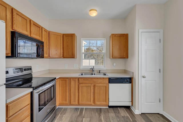 kitchen with white dishwasher, a sink, black microwave, light wood-style flooring, and electric range