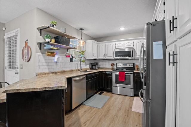 2321 Chimney Hills Dr, Soddy Daisy, TN 37379 - kitchen featuring appliances with stainless steel finishes, a sink, light wood-type flooring, white cabinets, and tasteful backsplash