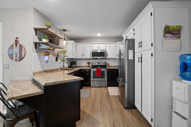 2321 Chimney Hills Dr, Soddy Daisy, TN 37379 - kitchen featuring appliances with stainless steel finishes, a sink, a peninsula, light wood finished floors, and white cabinetry