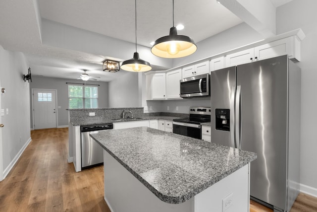 kitchen with appliances with stainless steel finishes, ceiling fan, a sink, white cabinetry, and a peninsula