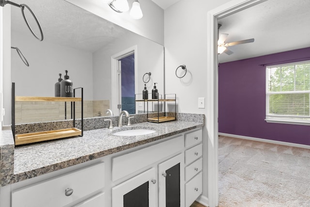 bathroom with a textured ceiling, vanity, a ceiling fan, and baseboards