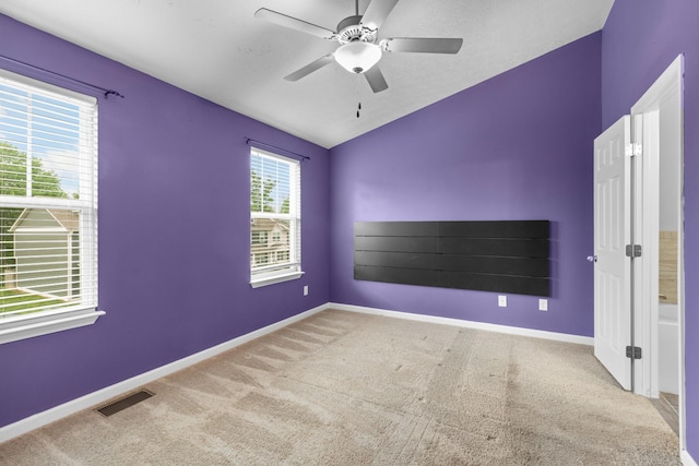 carpeted empty room featuring baseboards, visible vents, a ceiling fan, and vaulted ceiling