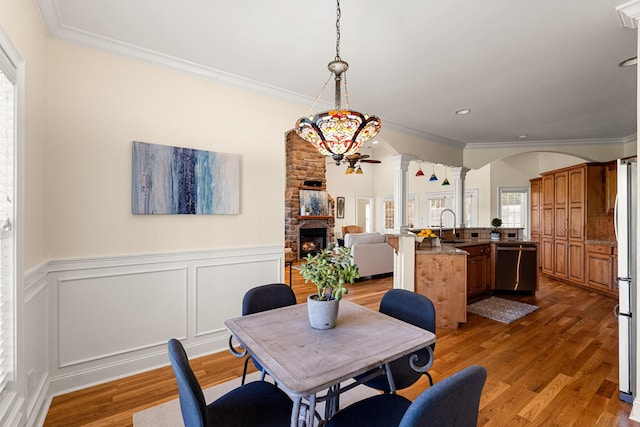 203 Tom Robinson Rd, Franklin, TN 37064 - dining area featuring ornamental molding, a fireplace, ornate columns, arched walkways, and wood finished floors