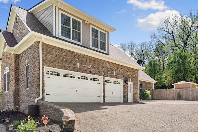 203 Tom Robinson Rd, Franklin, TN 37064 - view of side of home featuring a shingled roof, an attached garage, fence, brick siding, and driveway