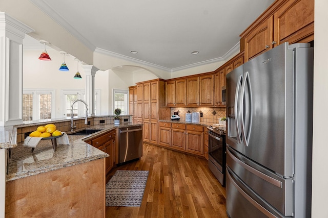 203 Tom Robinson Rd, Franklin, TN 37064 - kitchen featuring a sink, appliances with stainless steel finishes, brown cabinetry, ornate columns, and decorative backsplash